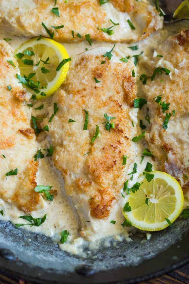 Chicken cooked in creamy garlic lemon sauce is simple and easy to make in one skillet in under 20 minutes! Close up of Creamy Lemon Garlic Chicken on a plate with fresh lemon slices.