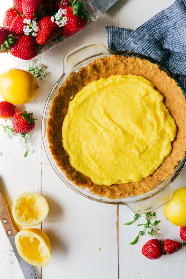 This Easy Lemon Pudding Pie is a creamy & light, slightly tangy, and very refreshing 3 layer dessert!ย Its buttery graham cracker crust is topped with a sweet and tart filling of lemon pudding and whipped cream.ย Insanely delicious and so quick and easy to make! Lemon filling in the pie with fresh strawberries and lemons on the side.