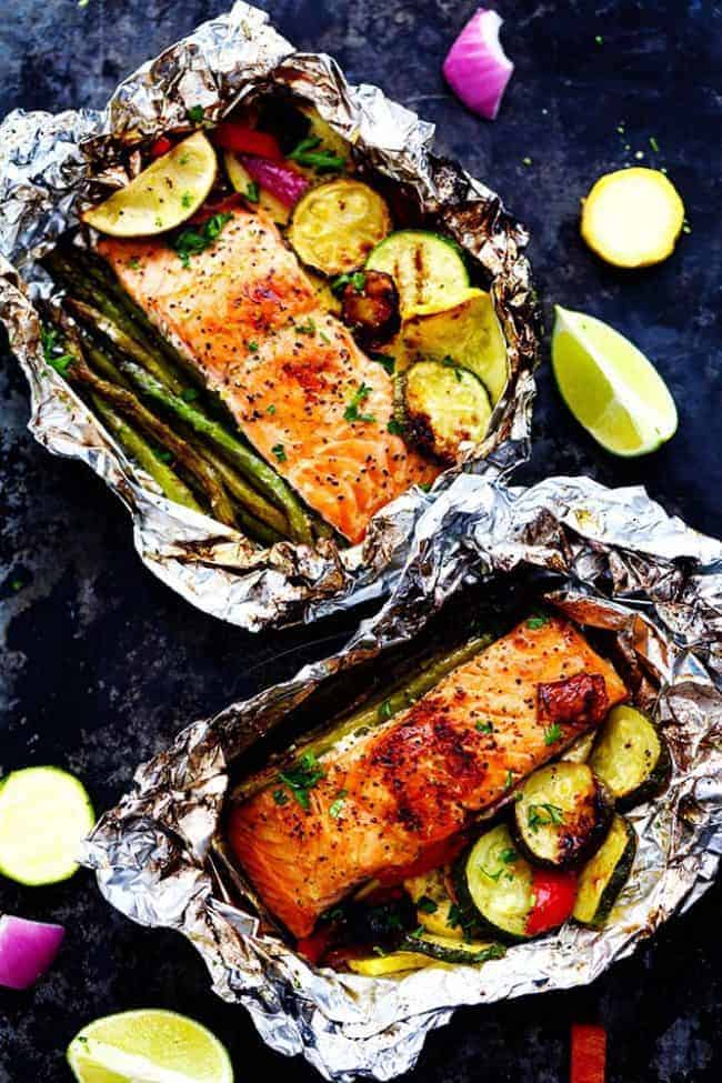 Lime Butter Salmon in Foil with Summer Veggies is grilled to tender and flaky perfection. The foil seals in the lime butter flavor and will be one of the BEST things that you eat! Lime Butter Salmon in Foil with Summer Veggies with the foil open to see the salmon.