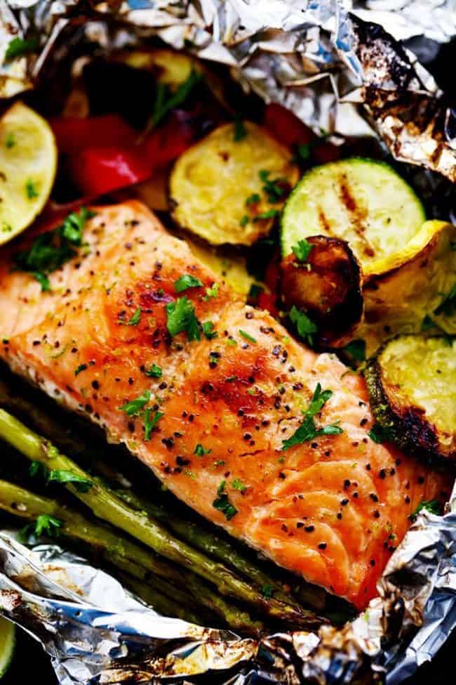 Lime Butter Salmon in Foil with Summer Veggies is grilled to tender and flaky perfection. The foil seals in the lime butter flavor and will be one of the BEST things that you eat! Close up photo of Lime Butter Salmon in Foil with Summer Veggies.