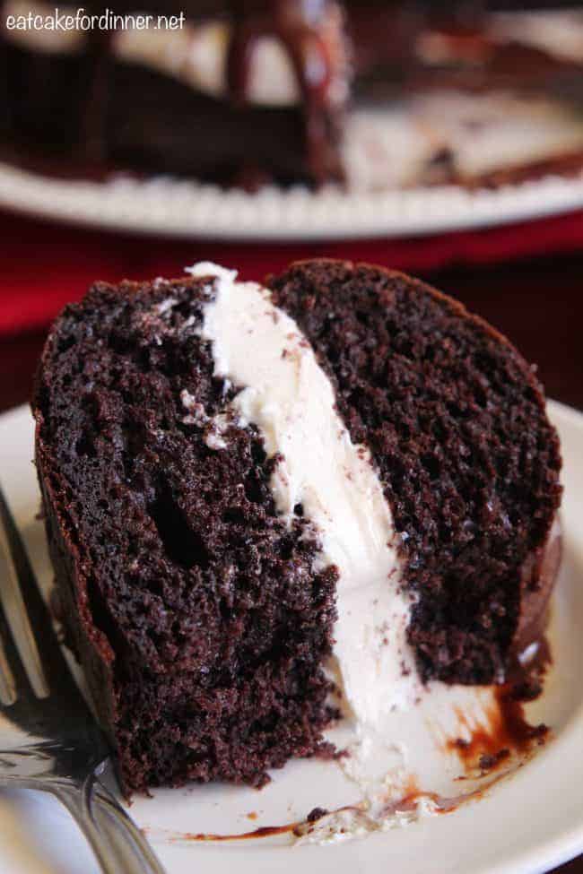 Chocolate Whoopie Pie Cake is a delicious spin on the classic whoopie pie! A dense chocolate cake filled with a soft and pillowy marshmallow filling and drizzled in a chocolate ganache. An up close photo fo Chocolate Whoopie Pie Cake on a white plate with a metal fork.