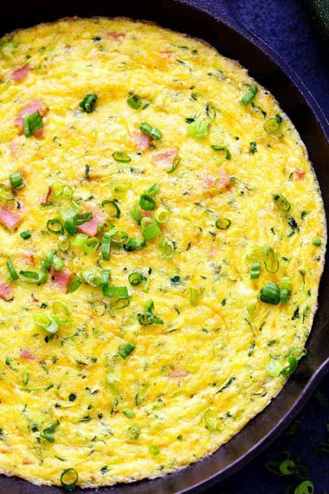 Ham and Cheddar Zucchini Frittata is filled with two cups of zucchini, ham, and cheddar cheese. It has such amazing flavor and will be devoured in no time at all! Close up of Ham and Cheddar Zucchini Frittata in a pan.