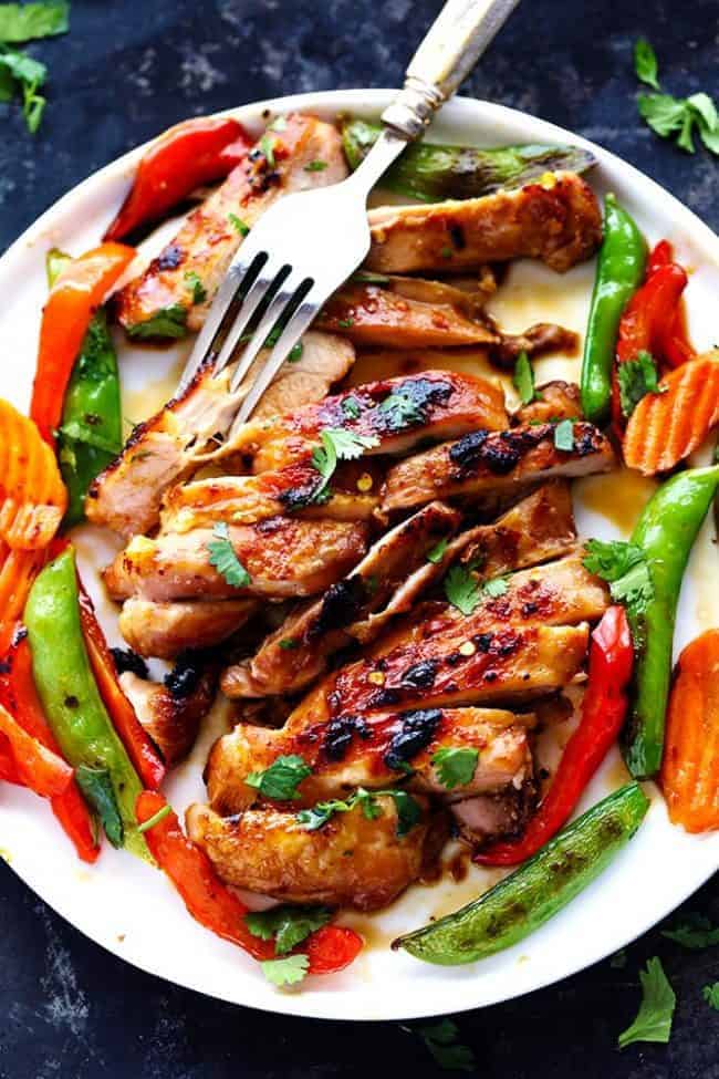 Thai Barbecue Chicken has a delicious thai marinade and is perfect served with some grilled veggies! The entire family will love this recipe! Thai Barbecue Chicken on a white plate with a metal fork.