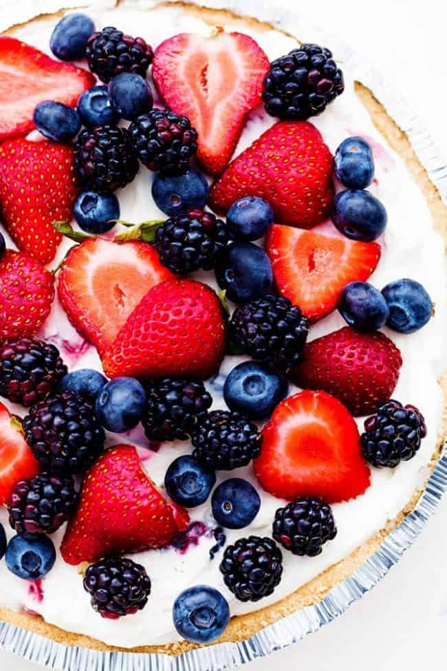 No Bake Very Berry Cheesecake comes together in just 10 minutes! It is filled with fresh summer berries hidden inside a creamy cheesecake and is incredible! No Bake Very Berry Cheesecake in a pie tin with fresh berries on top.