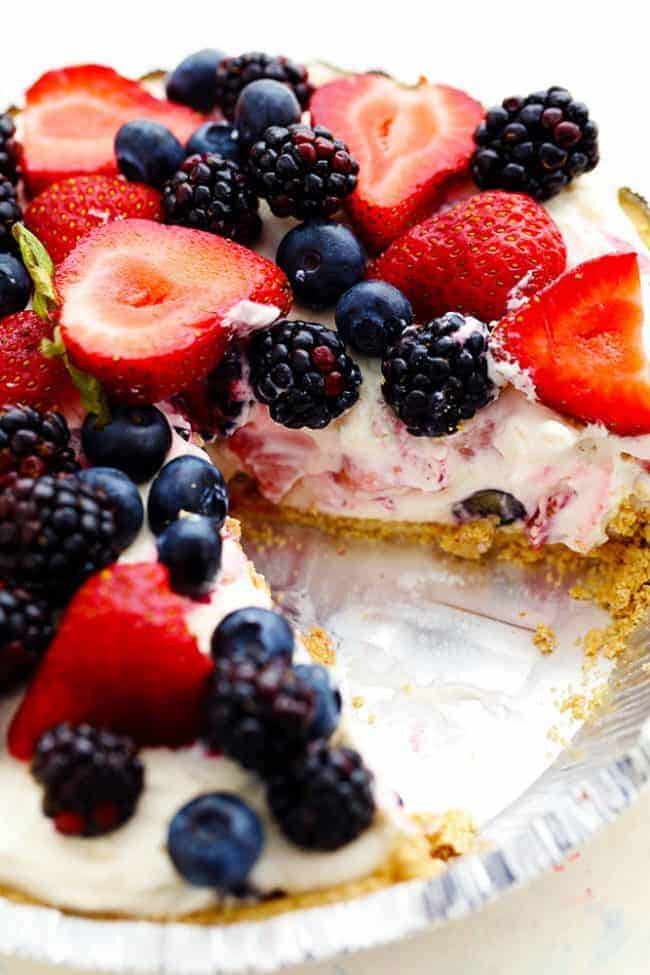 No Bake Very Berry Cheesecake comes together in just 10 minutes! It is filled with fresh summer berries hidden inside a creamy cheesecake and is incredible! No Bake Very Berry Cheesecake in a pie tin with a slice removed.