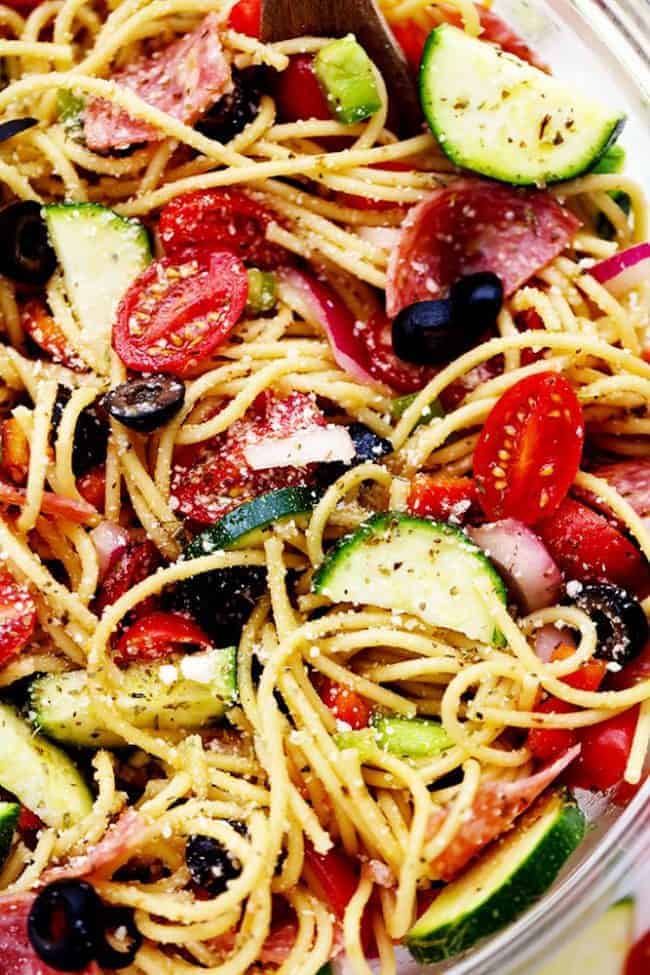 Italian Spaghetti Salad is made with spaghetti, fresh summer veggies, salami and tossed in a homemade zesty Italian dressing. This is a summer potluck must! Italian Spaghetti Salad in a clear bowl.