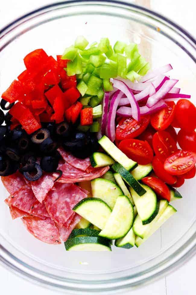 Italian Spaghetti Salad is made with spaghetti, fresh summer veggies, salami and tossed in a homemade zesty Italian dressing. This is a summer potluck must! Ingredients for Italian Spaghetti Salad in a clear bowl.