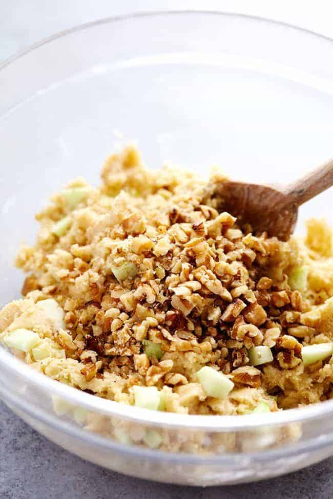 Apple Cream Cheese Crumb Muffins are the perfect buttery and moist apple walnut muffins with a hidden cream cheese center. Topped with a cinnamon sugar crumb topping these are the perfect fall muffins! Apple cream cheese, muffin ingredients in a glass bowl being stirred together with the wooden spoon.