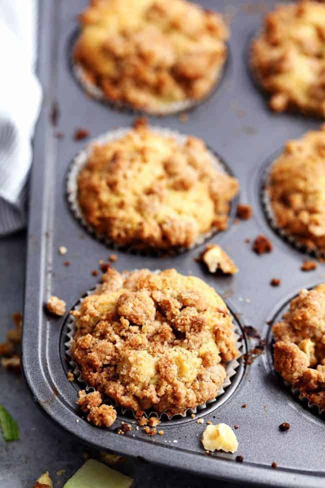 Apple Cream Cheese Crumb Muffins are the perfect buttery and moist apple walnut muffins with a hidden cream cheese center. Topped with a cinnamon sugar crumb topping these are the perfect fall muffins! Apple cream cheese Crumb Muffins in a muffin tin.