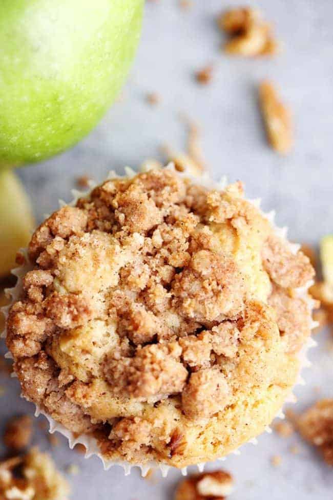 Apple Cream Cheese Crumb Muffins are the perfect buttery and moist apple walnut muffins with a hidden cream cheese center. Topped with a cinnamon sugar crumb topping these are the perfect fall muffins! Overhead shot of an apple cream cheese muffin.