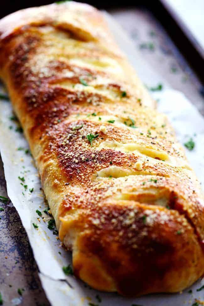 BBQ Chicken Stromboli is full of melty provolone cheese, chicken, caramelized red onions and sweet and tangy bbq sauce. This makes an amazing quick and easy meal or appetizer! BBQ chicken Stromboli baked on a baking sheet with parchment paper.