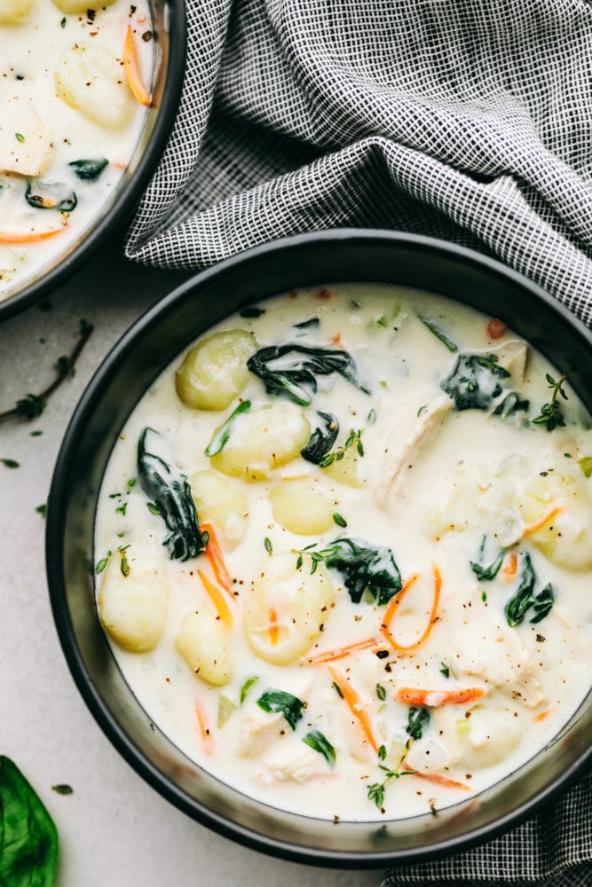 Creamy Chicken Gnocchi Soupย has a thick and rich broth with shredded carrots, celery, chopped spinach, gnocchi and chicken hidden throughout. This tastes even better than the Olive Garden! Chicken gnocchi soup in a black bowl.