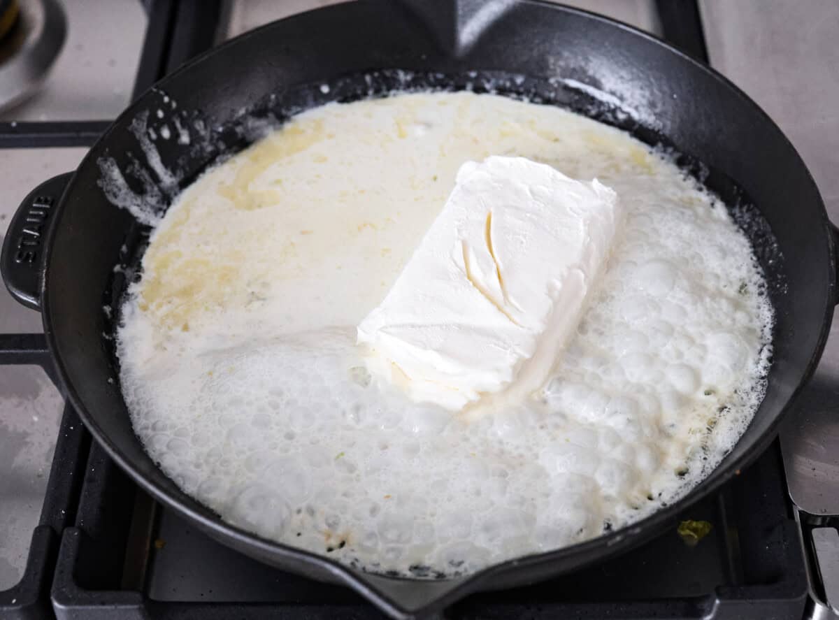 Creamy Parmesan Pasta Roni uses just 6 ingredients and one pan! It's loaded with creamy parmesan sauce and perfectly cooked al denta noodles. Your whole family will go crazy over this delicious, quick, easy meal. Angle s hot of butter, garlic, cream cheese, and heavy cream melting in a skillet.