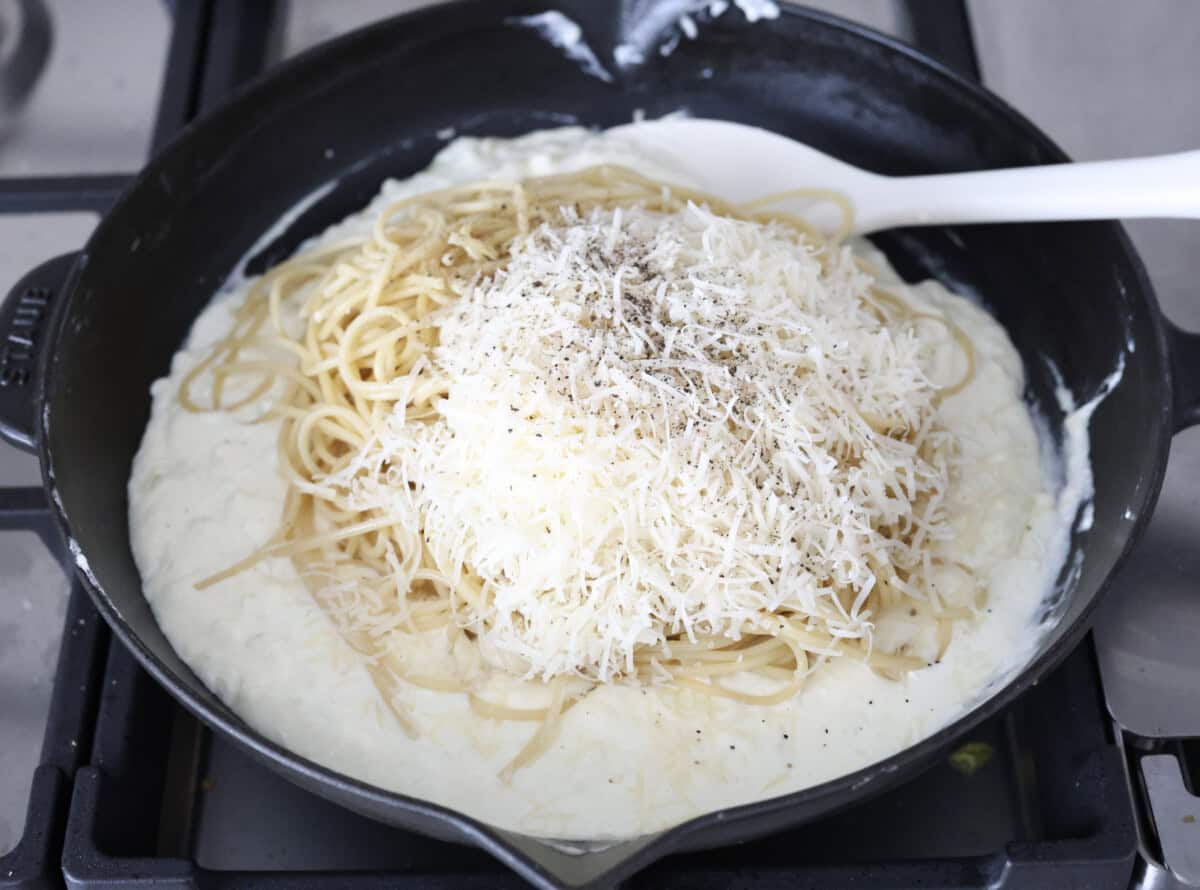 Creamy Parmesan Pasta Roni uses just 6 ingredients and one pan! It's loaded with creamy parmesan sauce and perfectly cooked al denta noodles. Your whole family will go crazy over this delicious, quick, easy meal. Overhead shot of the noodles, parmesan cheese, salt and pepper added to the cream cheese and heavy cream mixture.