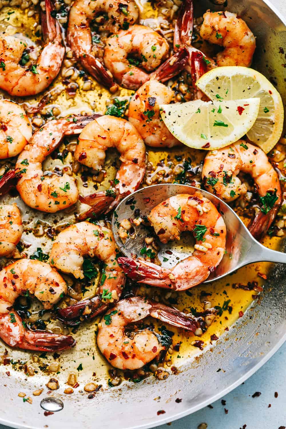 Brown Butter Spicy Garlic Shrimp is an incredibly easy meal that is ready in under 10 minutes! The brown butter flavor is so luxurious over the spicy garlic shrimp. It will wow your family! Brown Butter Spicy Garlic Shrimp being scooped into a spoon.