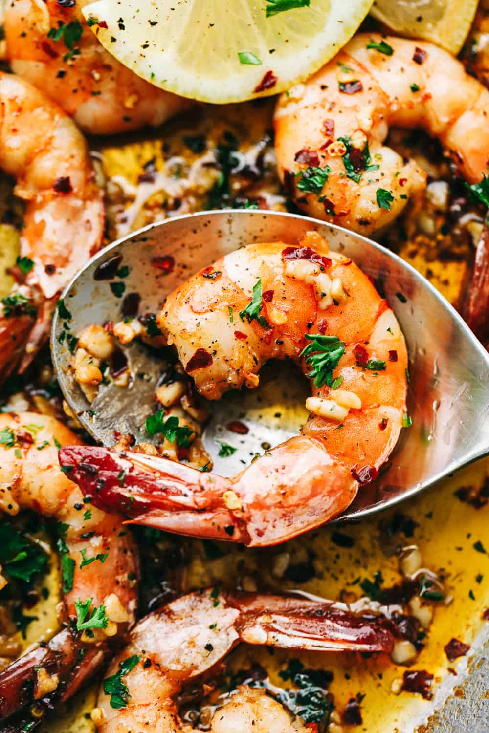 Brown Butter Spicy Garlic Shrimp is an incredibly easy meal that is ready in under 10 minutes! The brown butter flavor is so luxurious over the spicy garlic shrimp. It will wow your family! scooping shrimp into a spoon.