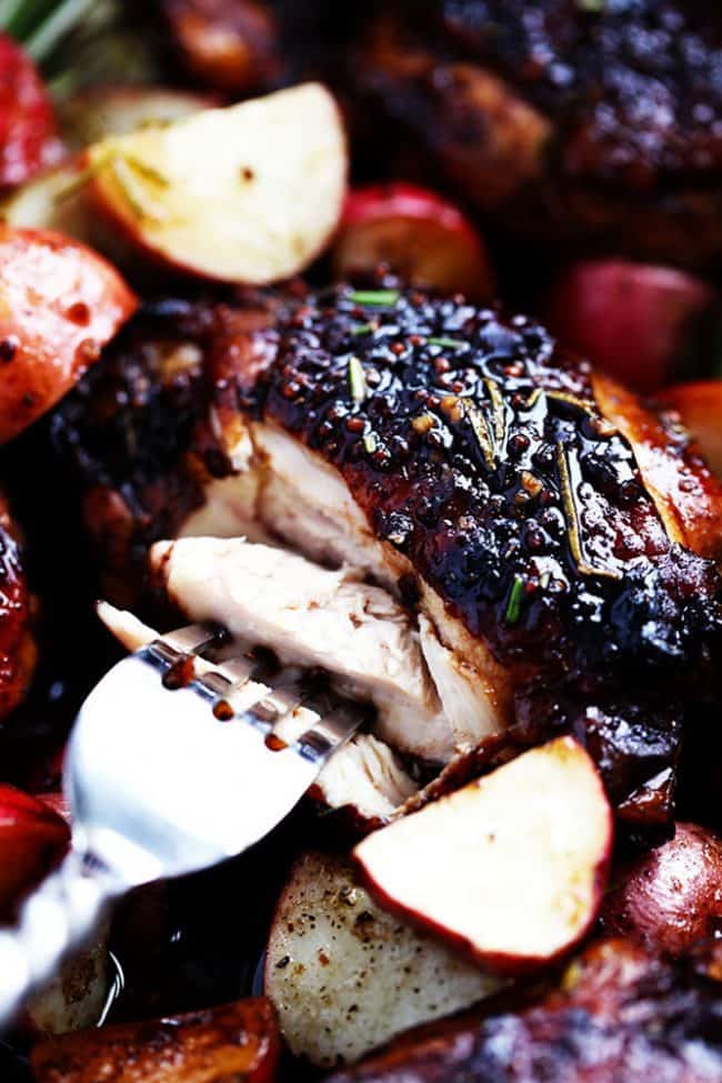 Glazed Honey Balsamic Chicken with Potatoes is a one pan meal with tender and juicy chicken glazed in a sweet and tangy honey balsamic sauce. Surrounded by crisp and tender potatoes this is one delicious meal! Up close photo of the glazed honey balsamic chicken being cut apart with a fork.