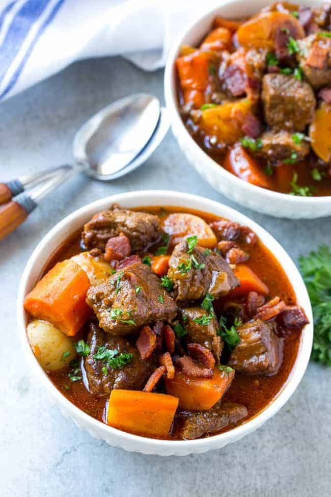 Beef Stew with Baconย is full of tender meat, colorful veggies and plenty of smoky bacon. A one pot meal that's perfect for cold weather! Beef stew with bacon and a white bowl.