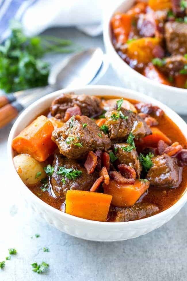 Beef Stew with Baconย is full of tender meat, colorful veggies and plenty of smoky bacon. A one pot meal that's perfect for cold weather! Beef stew with bacon and a white bowl.