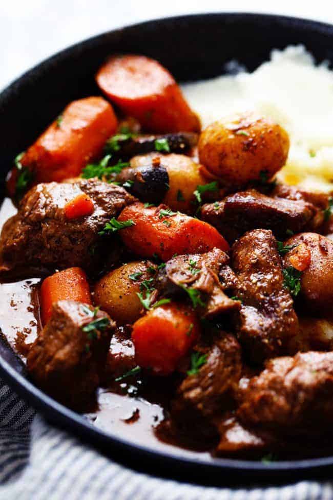 Slow Cooker Beef Bourguignon has crazy tender melt in your mouth beef and hearty veggies slow cooked to perfection in a rich sauce. ย This meal is comforting and perfect for the cold months ahead! slow Cooker Beef Bourguignon with mashed potatoes on a plate up close photo
