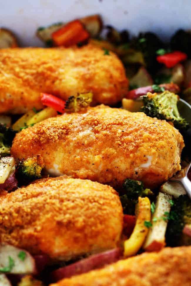 One Pan Crispy Parmesan Paprika Chicken with Vegetables has tender and juicy chicken with a crispy parmesan paprika breading surrounded by veggies. It it is full of flavor and makes an amazing one pan dinner your family will love! Crispy Parmesan paprika chicken laying on top of vegetables.