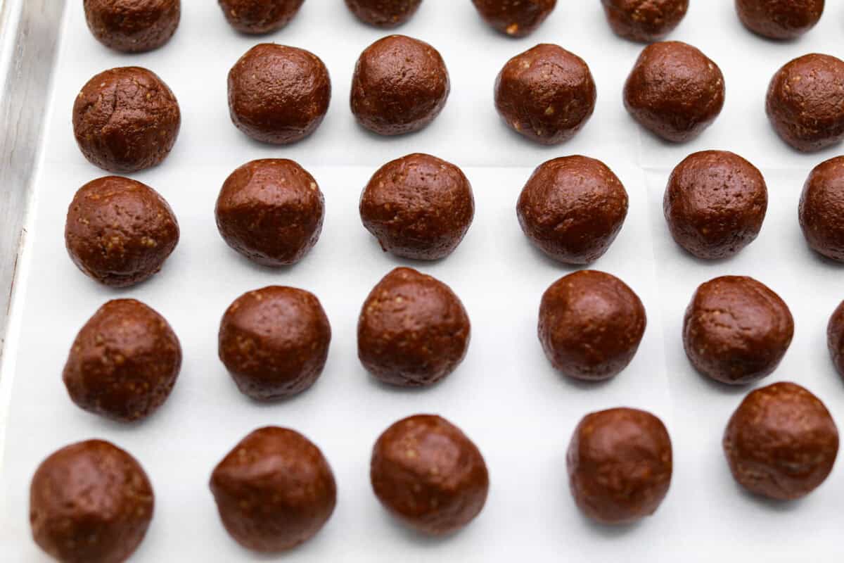 Chocolate Snowball Cookies are tender chocolate cookies with the best texture! A buttery cookie made with cocoa powder and ground walnuts gets coated in sweet powdered sugar. Make this classic holiday cookie a tradition every year! Sixth photo of the dough scooped into balls.
