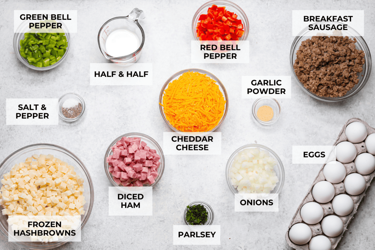 This Slow Cooker Breakfast Casserole is quick and easy to put together! Breakfast can be cooked in the slow cooker while you're sleeping! This casserole is loaded up with seasoned sausage, diced hash browns, tender vegetables, eggs, and cheese. Overhead shot of labeled ingredients.
