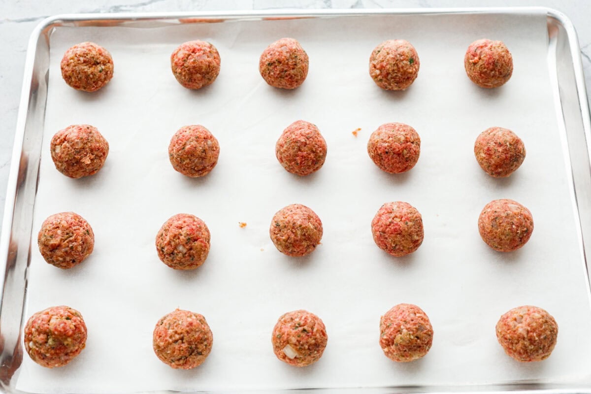 Mozzarella Stuffed Meatballs take classic meatballs to the next level! Tender and juicy with melty cheese on the inside. Serve these meatballs as a party appetizer or over spaghetti noodles for a hearty meal! Fourth photo of the mozzarella stuffed meatballs placed on a baking sheet to bake.