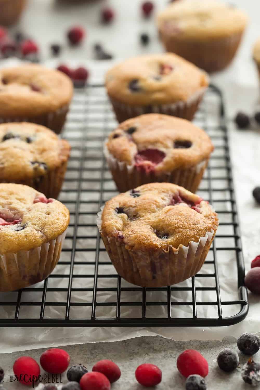 These Fruit Explosion Muffins are packed with berries and have a strawberry surprise in the center! They are just as good as your bakery favorite but madeย completely from scratch. These Fruit Explosion Muffins on a cooling rack.