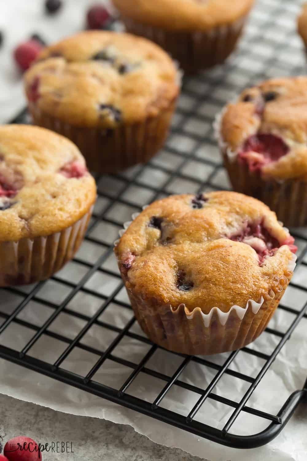 These Fruit Explosion Muffins are packed with berries and have a strawberry surprise in the center! They are just as good as your bakery favorite but madeย completely from scratch. These Fruit Explosion Muffins on a cooling rack.