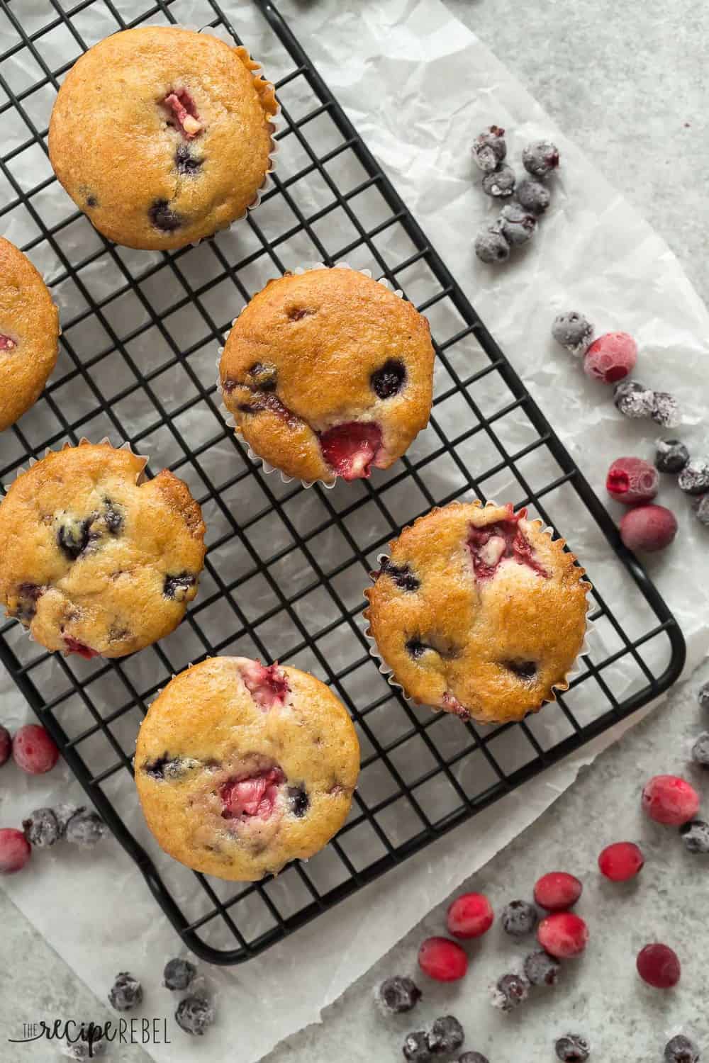 These Fruit Explosion Muffins are packed with berries and have a strawberry surprise in the center! They are just as good as your bakery favorite but madeย completely from scratch. These Fruit Explosion Muffins areal view on a cooling rack.