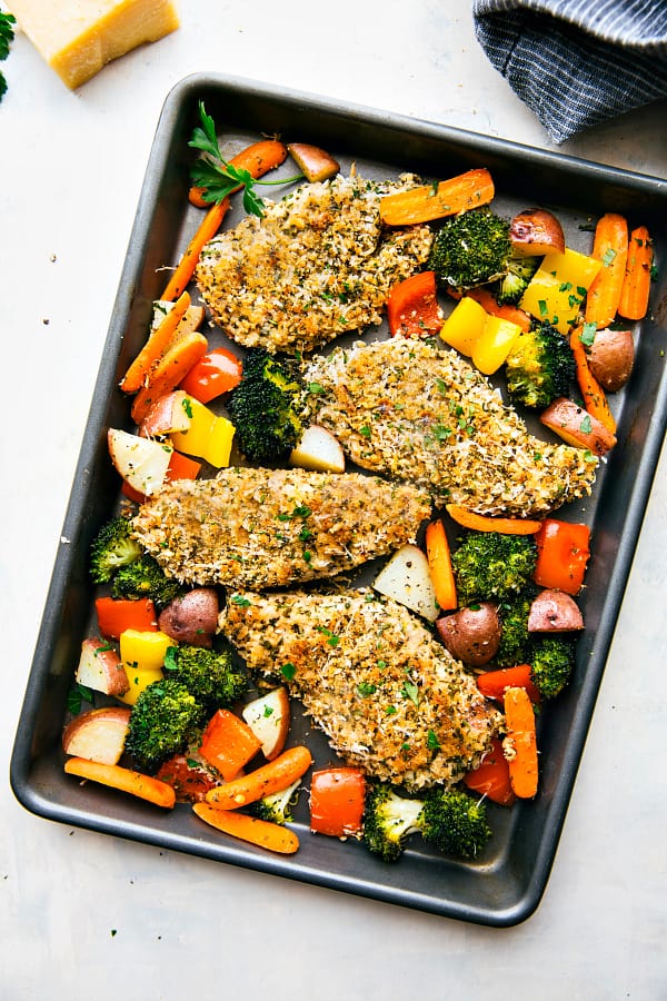 One Pan Crispy Walnut Herb Chicken and Vegetables is a delicious meal all made in one pan! The chicken gets coated with a nutty walnut herb coating and is surrounded by tender veggies. This is sure to be a hit!ย One Pan Crispy Walnut Herb Chicken and Vegetables in a baking tray.