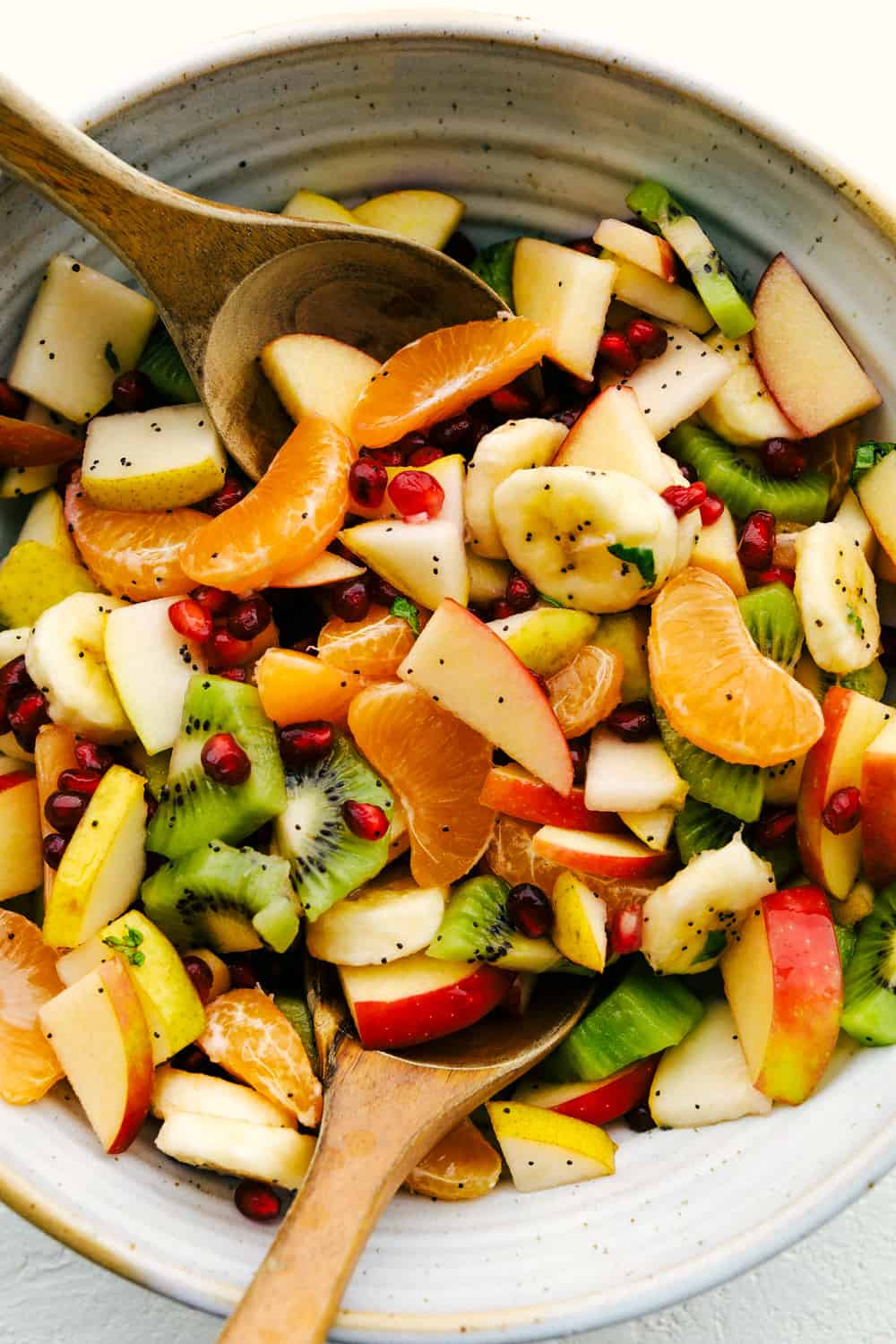 The Best Winter Fruit Salad is filled with clementines, kiwi, pears, apples, and pomegranate, then tossed in sweet tart honey lime poppy seed dressing. These are all fruits that are in season in the fall and winter and when tossed with the most delicious dressing it's a dinner winner for sure. Serving up fruit salad with honey lime dressing.