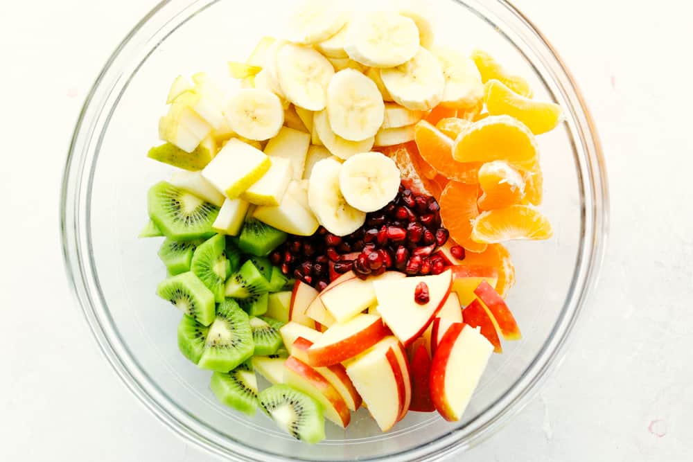 The Best Winter Fruit Salad is filled with clementines, kiwi, pears, apples, and pomegranate, then tossed in sweet tart honey lime poppy seed dressing. These are all fruits that are in season in the fall and winter and when tossed with the most delicious dressing it's a dinner winner for sure. Winter Fruit Salad with bananas apples, oranges kiwi and pomegranates.