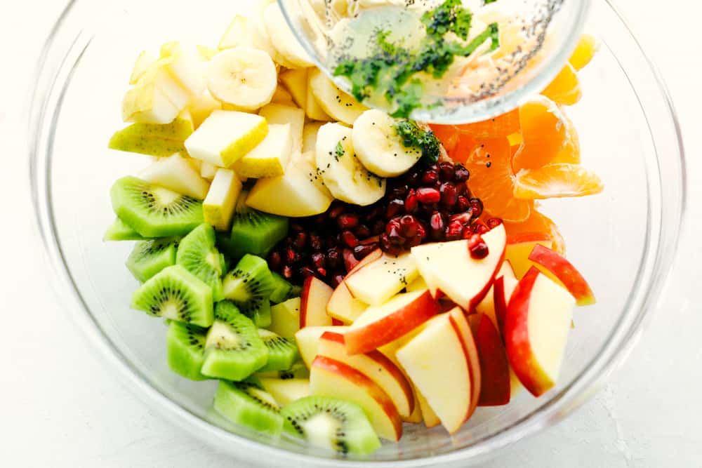 The Best Winter Fruit Salad is filled with clementines, kiwi, pears, apples, and pomegranate, then tossed in sweet tart honey lime poppy seed dressing. These are all fruits that are in season in the fall and winter and when tossed with the most delicious dressing it's a dinner winner for sure. Winter Fruit Salad with bananas apples, oranges kiwi and pomegranates with poppyseed dressing.