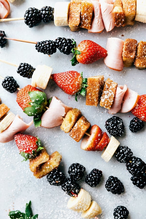Canadian Bacon and French Toast Kabobs make a fun and delicious breakfast! Loaded up with fresh fruit, canadian bacon, and french toast these will become a new favorite way to eat breakfast!ย Canadian Bacon and French Toast Kabobs laid on a table.
