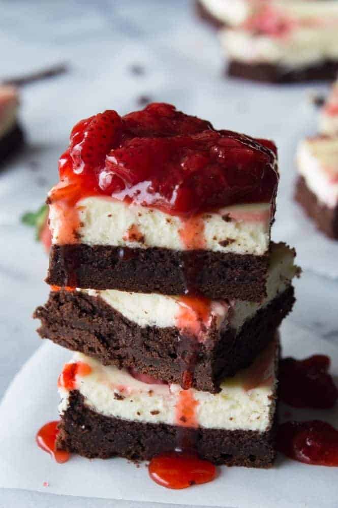 Strawberry Cheesecake Brownies. These homemade brownies are loaded up with a layer of creamy cheesecake then swirled with a sweet strawberry sauce for a pop of color and flavor! Spoon the extra strawberry sauce over the top for an extra special dessert!ย Stack of Strawberry Cheesecake Brownies.