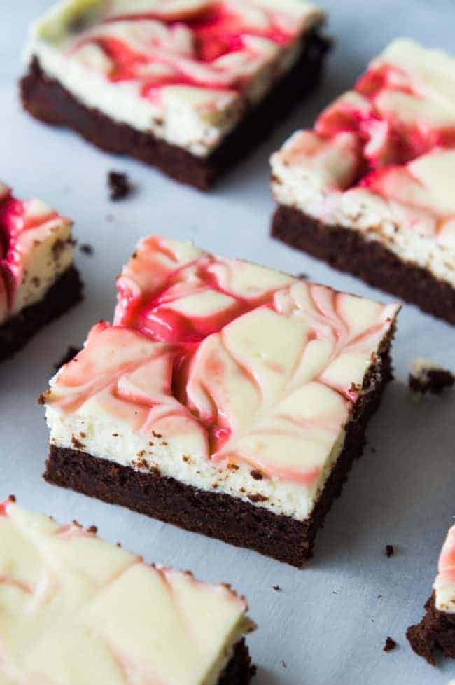 Strawberry Cheesecake Brownies. These homemade brownies are loaded up with a layer of creamy cheesecake then swirled with a sweet strawberry sauce for a pop of color and flavor! Spoon the extra strawberry sauce over the top for an extra special dessert!ย Strawberry Cheesecake Brownies in rows.