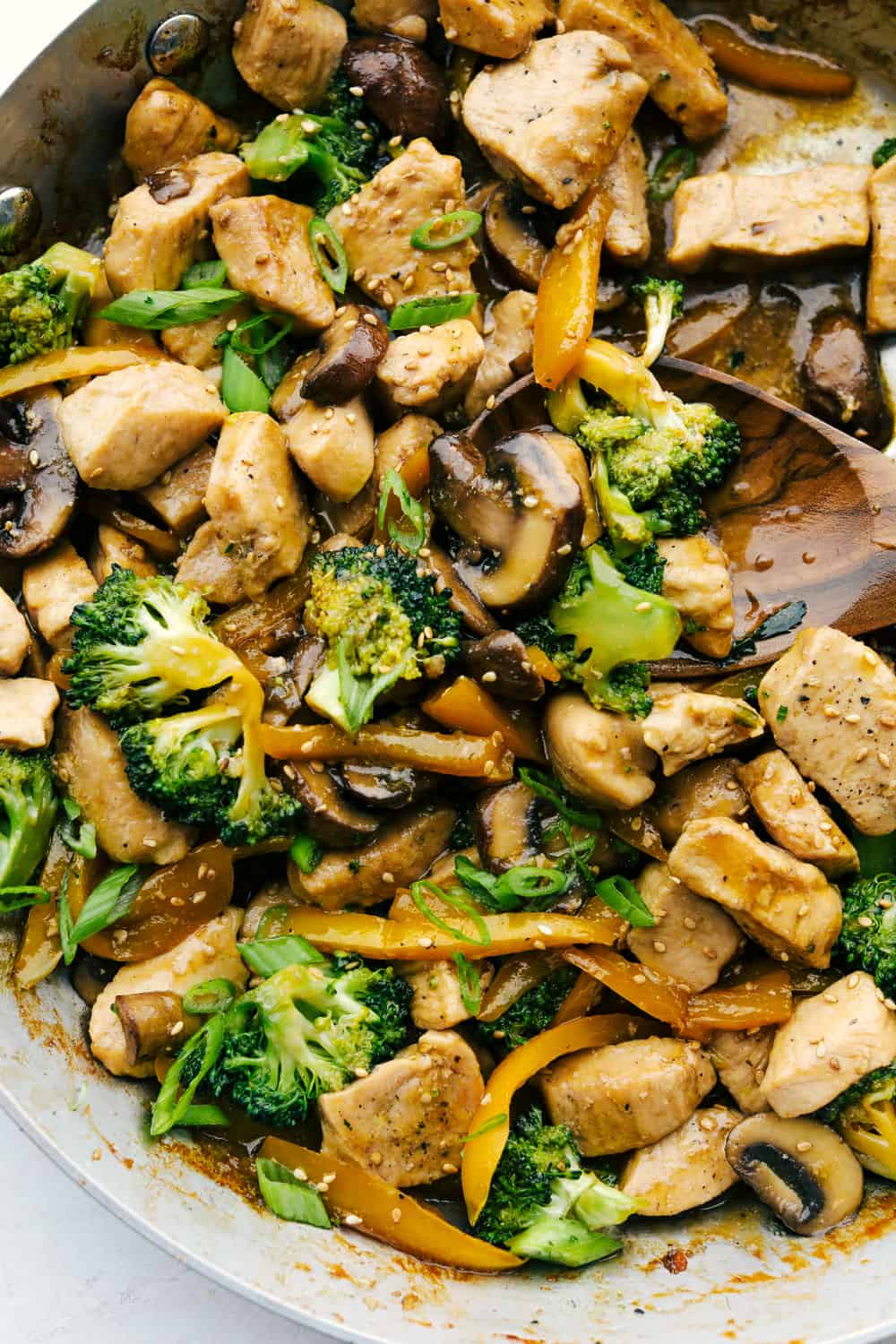 This garlic chicken stir fry is a quick and easy dinner that's perfect for those busy weeknights. Cubes of chicken are cooked with colorful veggies and tossed in a flavorful garlic sauce for a meal that's way better than take out! Stirring the chicken, broccoli and mushrooms all together.