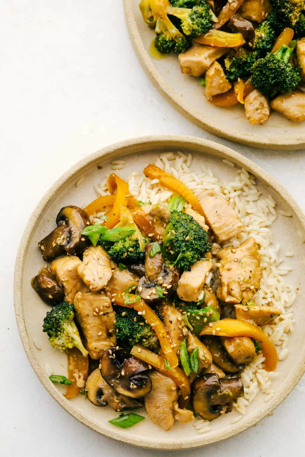 This garlic chicken stir fry is a quick and easy dinner that's perfect for those busy weeknights. Cubes of chicken are cooked with colorful veggies and tossed in a flavorful garlic sauce for a meal that's way better than take out! Garlic Chicken Stir fry on a plate with rice.
