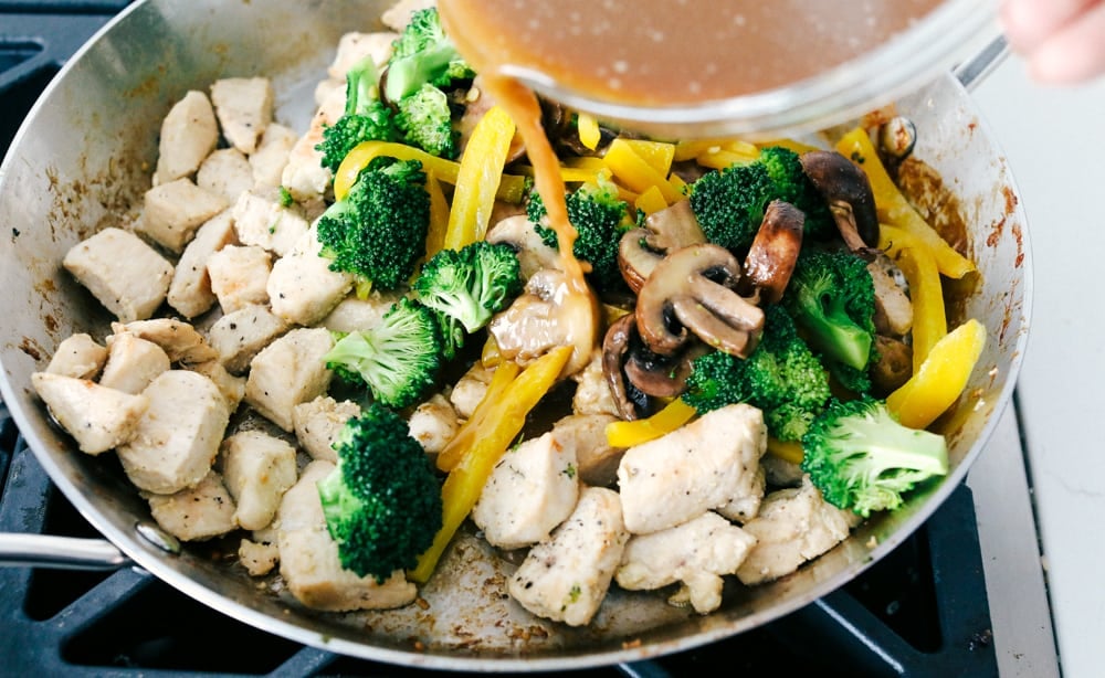 This garlic chicken stir fry is a quick and easy dinner that's perfect for those busy weeknights. Cubes of chicken are cooked with colorful veggies and tossed in a flavorful garlic sauce for a meal that's way better than take out! Adding the vegetables to the chicken and the sauce.