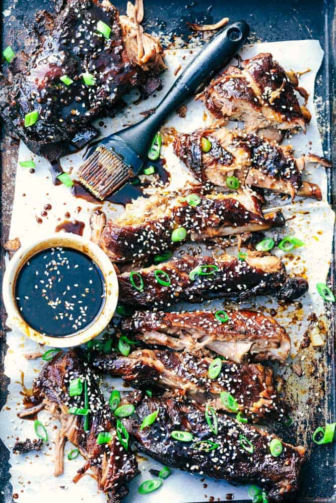 Slow Cooker Sticky Asian Ribs with Sticky Sauce are the very best fall of the bone tender ribs you will ever make! Slow cooked to perfection in a sweet and tangy asian sauce. They get slathered right before serving in a finger licking good sticky sauce! Slow Cooker Sticky Asian Ribs with Sticky Sauce and sauce with a brush to brush it on.