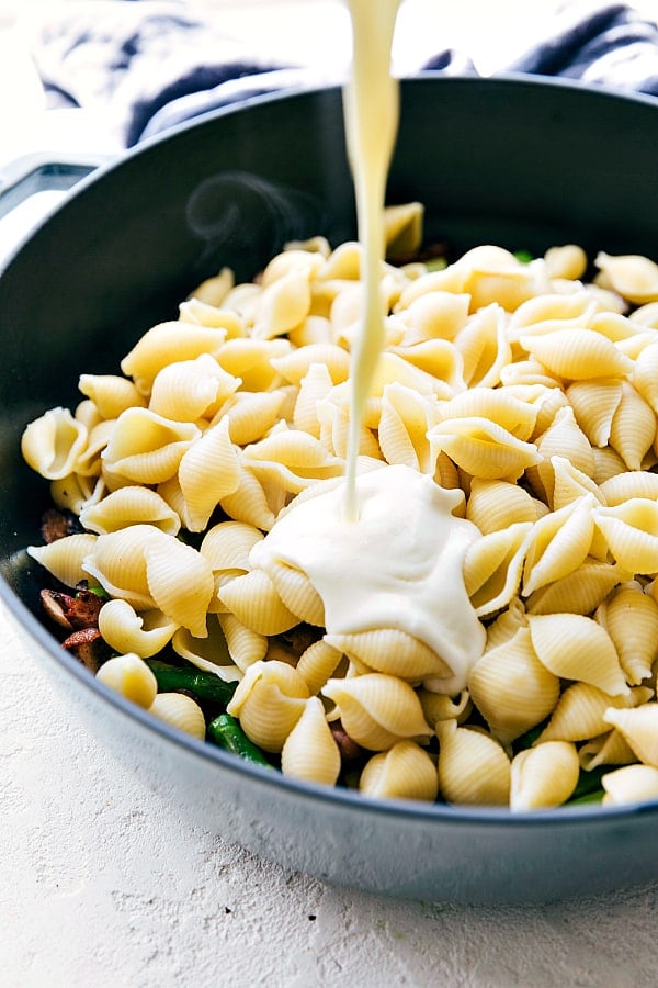 You will not find a better creamy and cheesy sauce than this one my friends. Pouring cheese sauce over the pasta in a skillet.