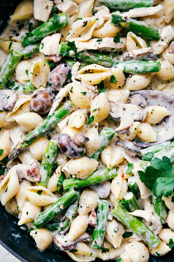 This is a family friendly meal that everyone is going to beg for you to make again and again! Close up on finished shells and asparagus with cheese sauce.