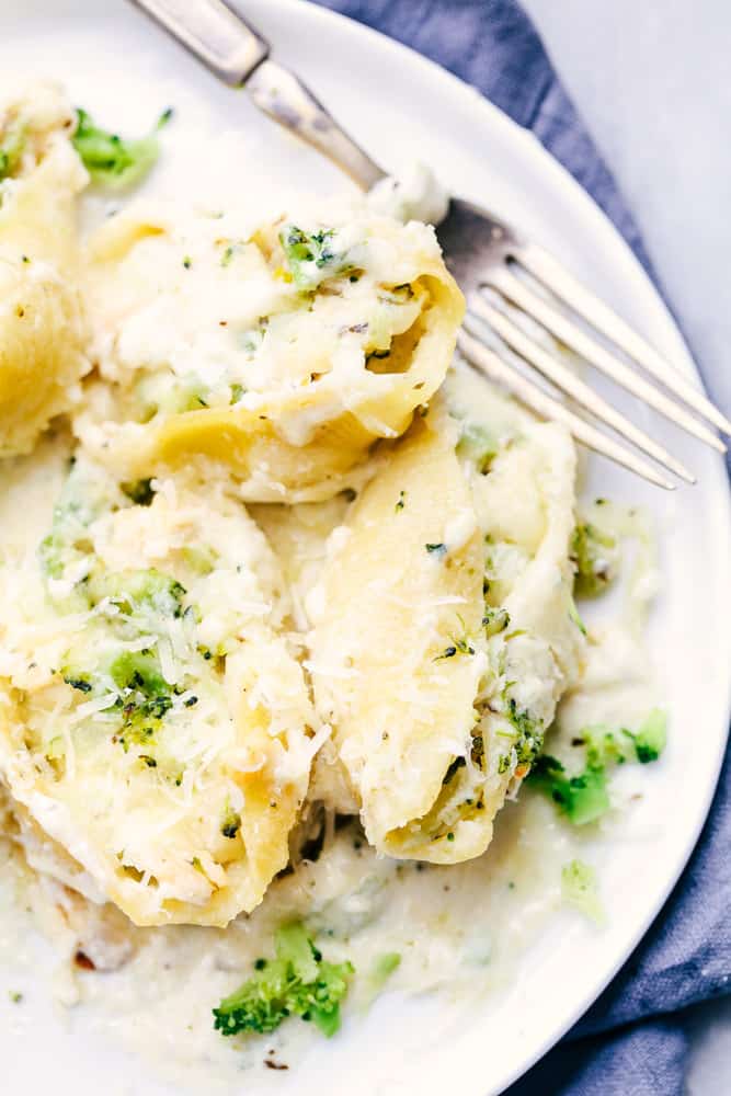 Chicken Broccoli Garlic Alfredo Shellsย are stuffed with tender chicken, cheese, broccoli, and homemade alfredo sauce. These shells are creamy, cheesy and out of this world delicious!ย Chicken Broccoli Garlic Alfredo Shells on a white serving plate.