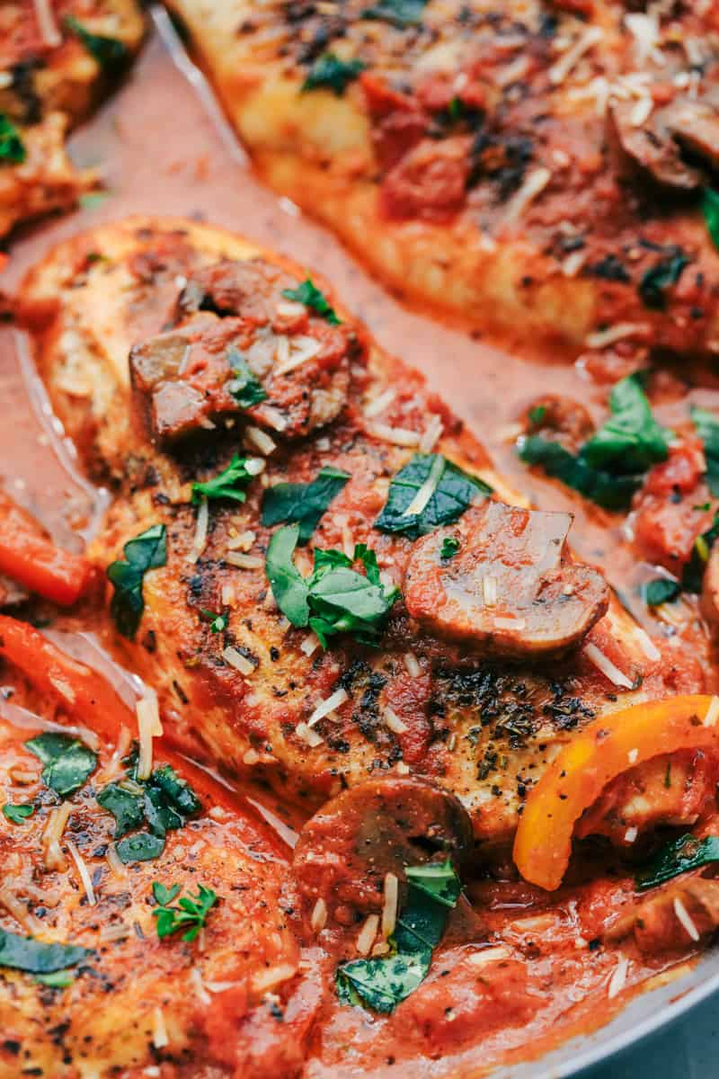 Creamy Skillet Chicken Cacciatore has the most amazing creamy red sauce with peppers, mushrooms, and fresh basil. The chicken is tender and juicy and on the dinner table in 30 minutes!ย Creamy Skillet Chicken Cacciatore close up.