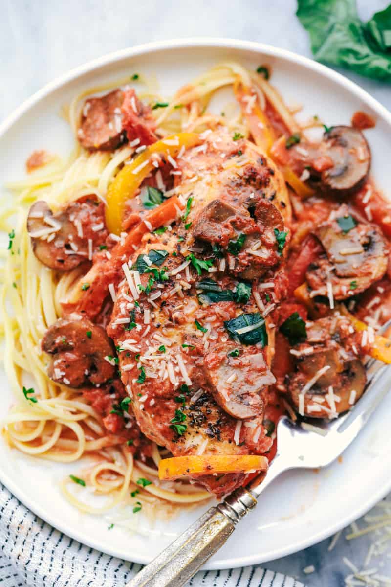 Creamy Skillet Chicken Cacciatore has the most amazing creamy red sauce with peppers, mushrooms, and fresh basil. The chicken is tender and juicy and on the dinner table in 30 minutes!ย Creamy Skillet Chicken Cacciatore on a plate.