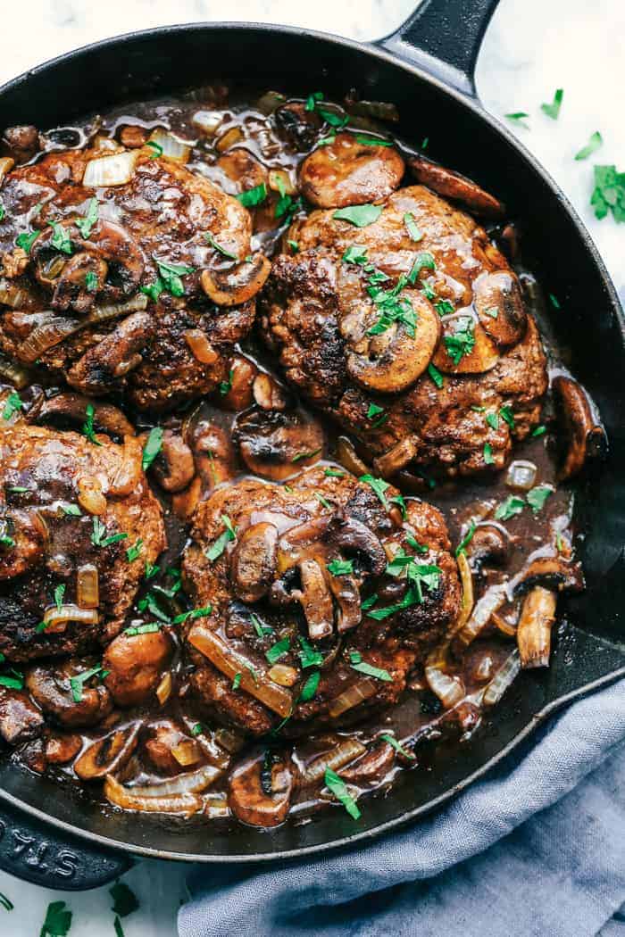 Skillet Salisbury Steak is a classic mealย with a mouthwatering tender beef patty drowning in a rich homemade brown gravy. Serve it over some mashed potatoes and peas and you have yourself a winner! Skillet Salisbury Steak in a cast iron pan.