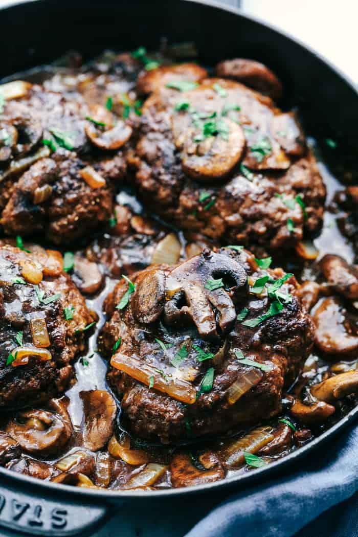 Skillet Salisbury Steak is a classic mealย with a mouthwatering tender beef patty drowning in a rich homemade brown gravy. Serve it over some mashed potatoes and peas and you have yourself a winner! Skillet Salisbury Steaks in a black cast iron pan.