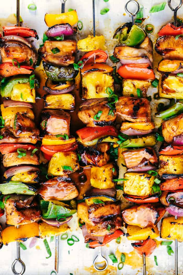 Grilled Hawaiian Teriyaki Chicken Skewers marinate in the very best homemade hawaiian teriyaki sauce! Loaded with peppers, fresh pineapple and red onions, these make an incredible and vibrant meal!ย Hawaiian Teriyaki Chicken Skewers laid in rows.